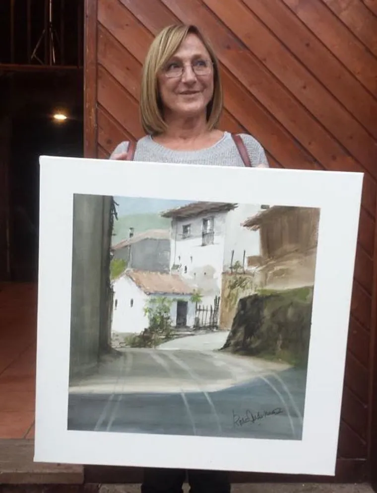Ganadora del certamen de pintura posando con su cuadro de una calle del pueblo